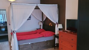 A room with a bed, a dresser, a lamp, and a ceiling light.