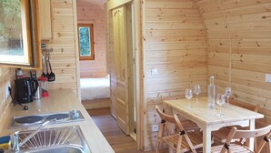 Interior acolhedor de uma cabana de madeira, com cozinha, mesa de jantar e cadeiras.