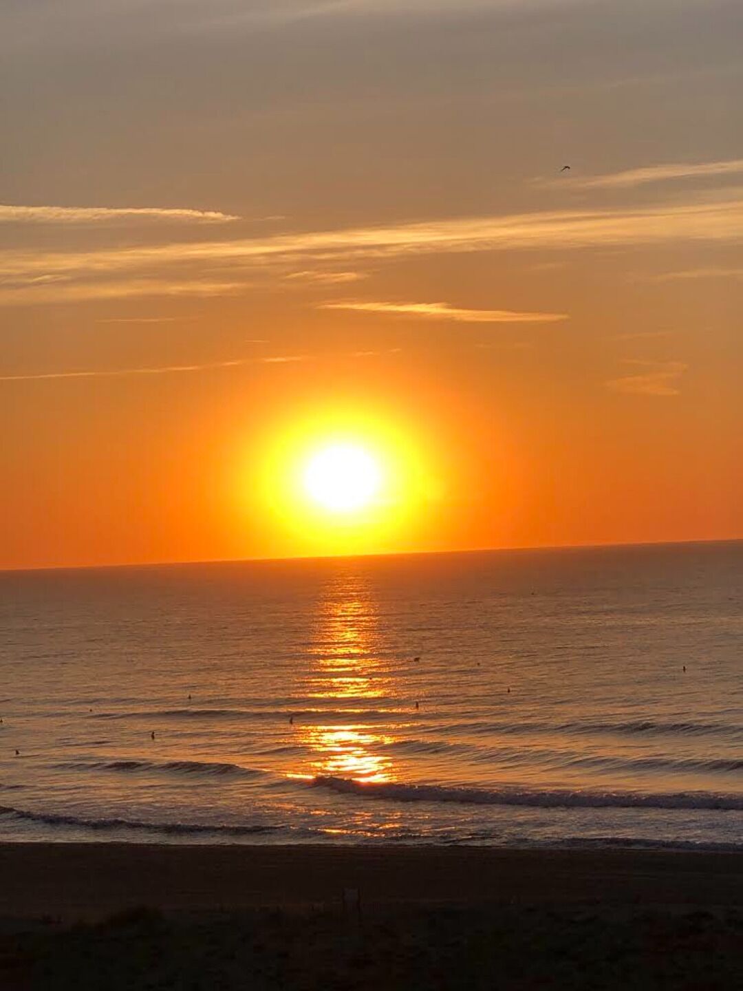 Een zonsondergang boven een rustige zee met een heldere horizon.