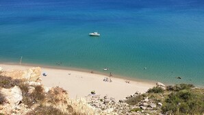A beach with clear turquoise water, a boat, and rocky terrain. - BARCARESA-LA PERLE SEA VIEW WATERFRONT AIR CONDITIONING WIFI (Port Leucate)