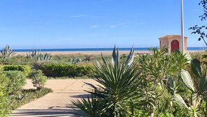 A pathway leading to a beach with a lamp post and a small building in the background. - BARCARESA-LA PERLE SEA VIEW WATERFRONT AIR CONDITIONING WIFI (Port Leucate)
