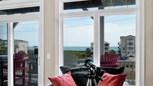 A balcony with a telescope, red and black cushions, and a view of the ocean and buildings. - Linens included - Amazing Views, Steps to Beach, Elevator and Fenced Yard (North Topsail Beach)