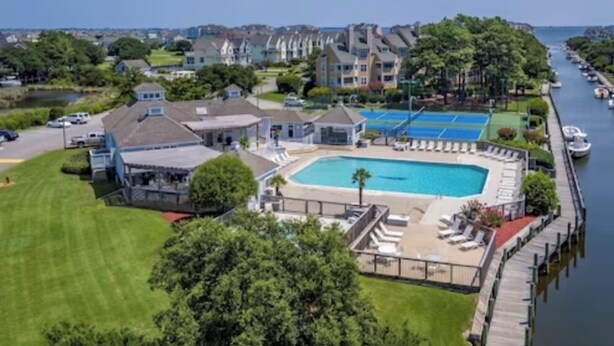 A waterfront property with a swimming pool, tennis courts, and a dock. - Offshore Addiction  (Manteo)