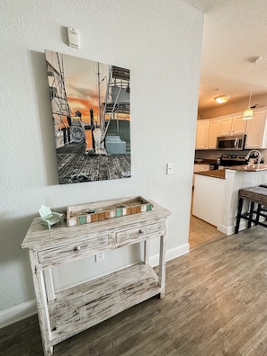 Relax in a spacious room with a console table, abstract art, and a modern kitchen.