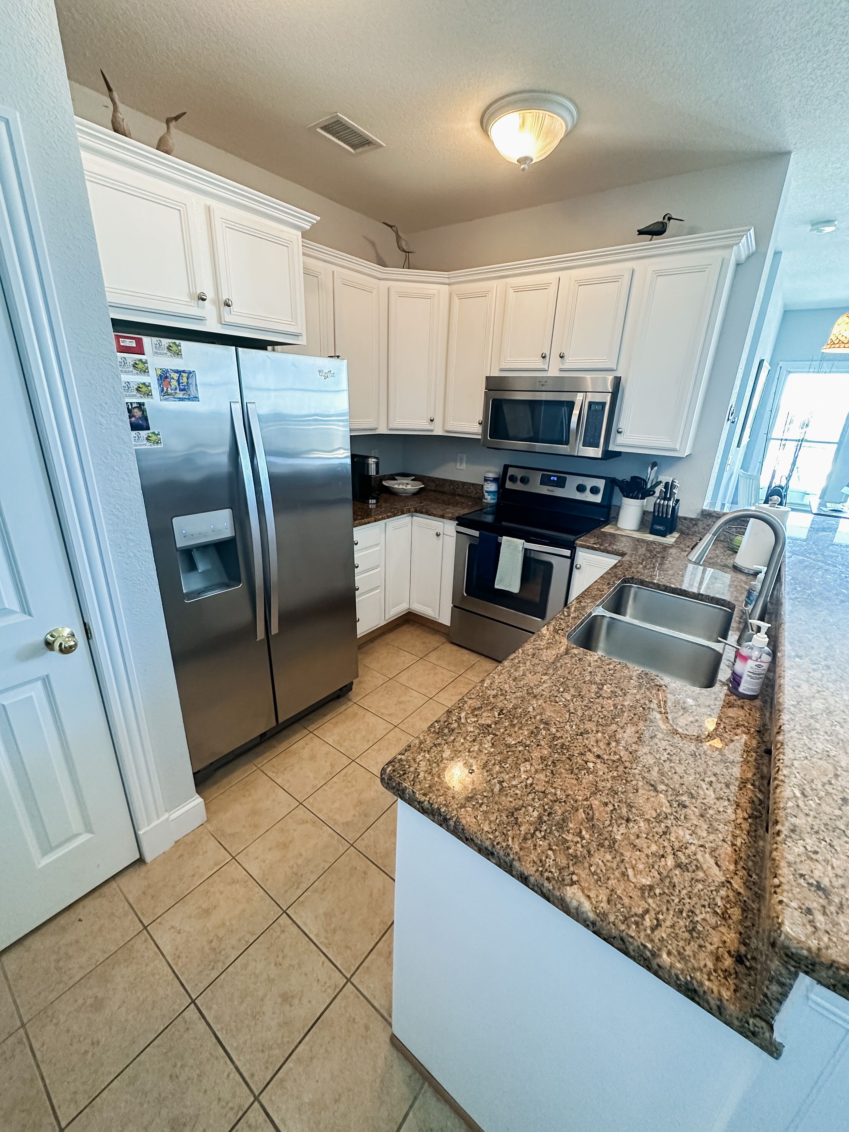 A modern kitchen with white cabinets, stainless steel appliances, and a granite countertop.