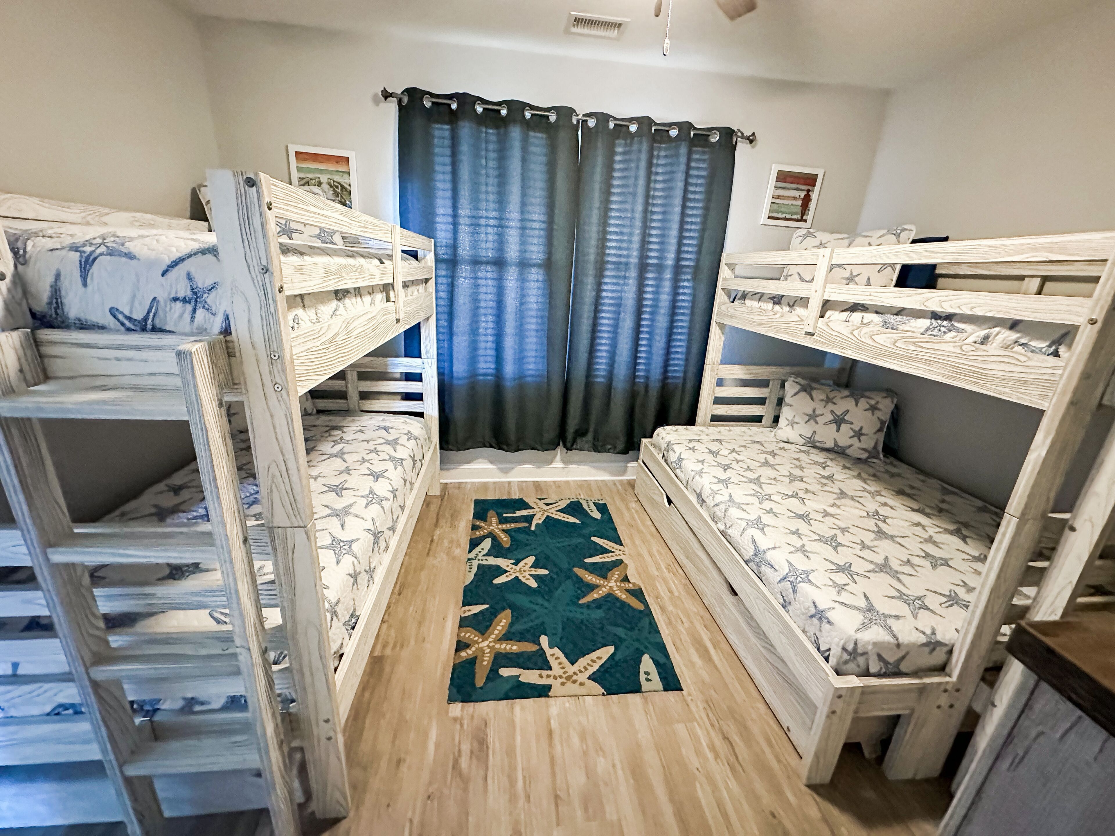 Een kamer met stapelbedden, een vloerkleed met sterrenpatroon en een raam met gordijnen.