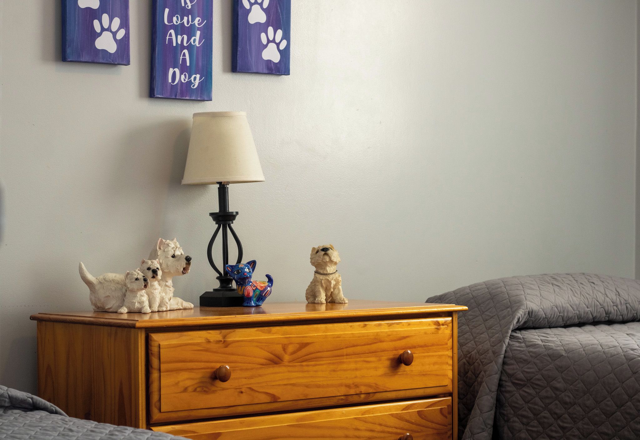 Eine hölzerne Kommode mit drei Hundfiguren, einer Lampe und zwei Wanddekorationen mit Pfotenabdrücken und der Aufschrift 'Love and a Dog'.