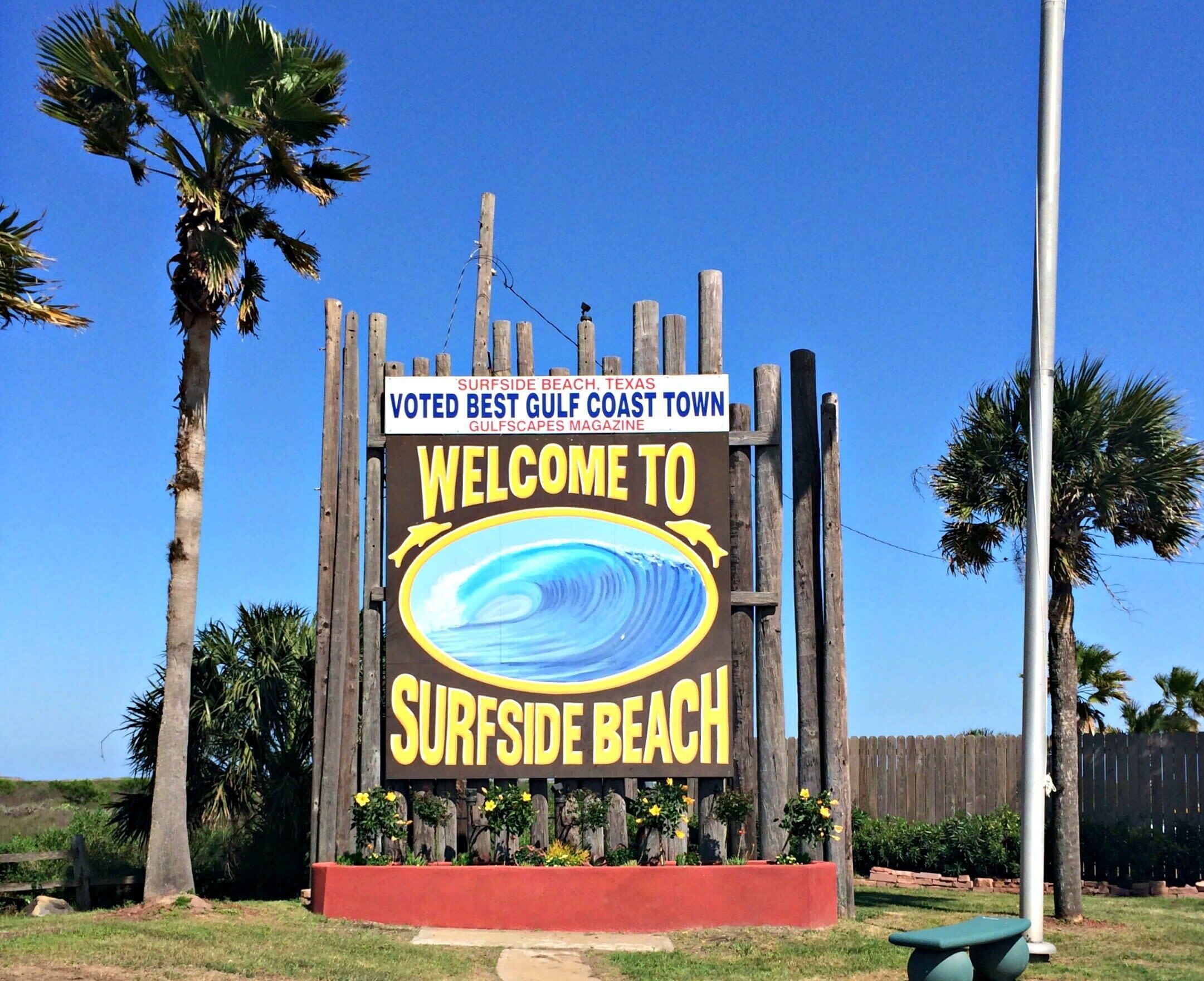 A sign welcoming visitors to Surfside Beach, Texas, with a beach scene illustration.