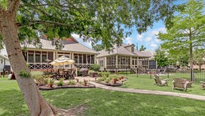 A building with a covered patio, outdoor seating, and a well-maintained lawn.