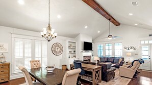 A spacious living area with a dining table, sofas, and a chandelier.