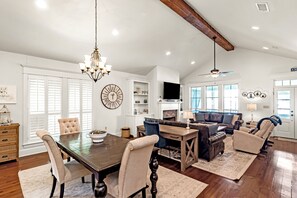 A spacious living area with a dining table, sofas, and a chandelier.