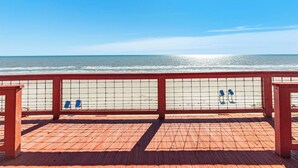A wooden deck with a view of the beach and ocean.