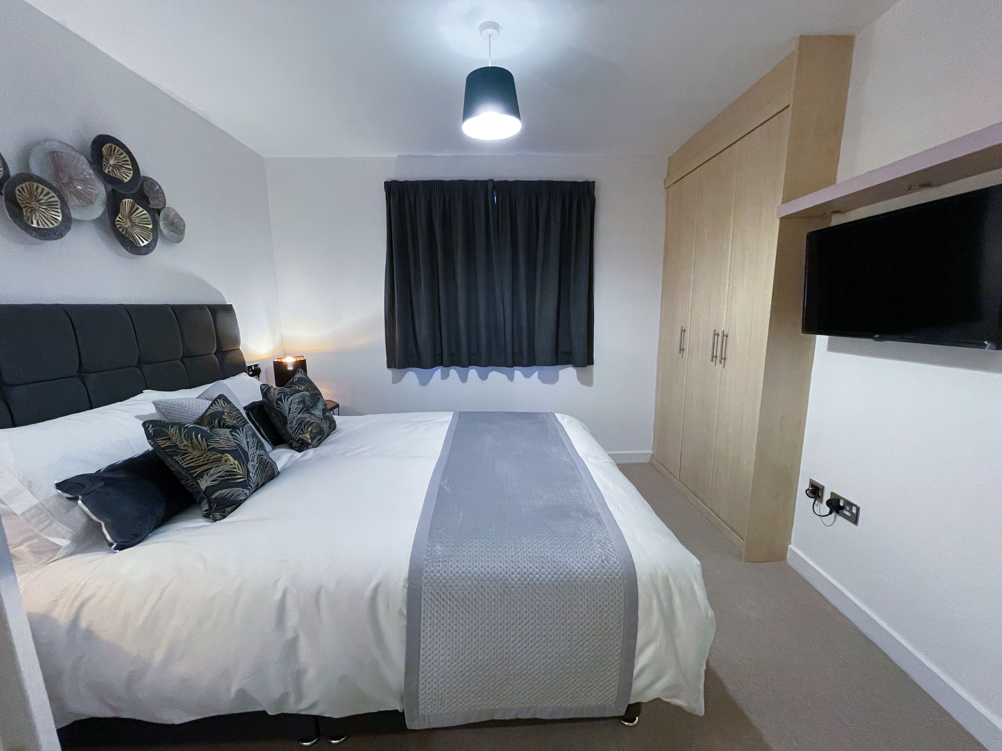 A bedroom with a bed, a nightstand, a TV, and a wardrobe.