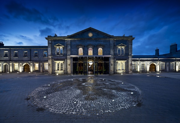 A historic building with a central entrance, large windows, and a cobblestone courtyard.