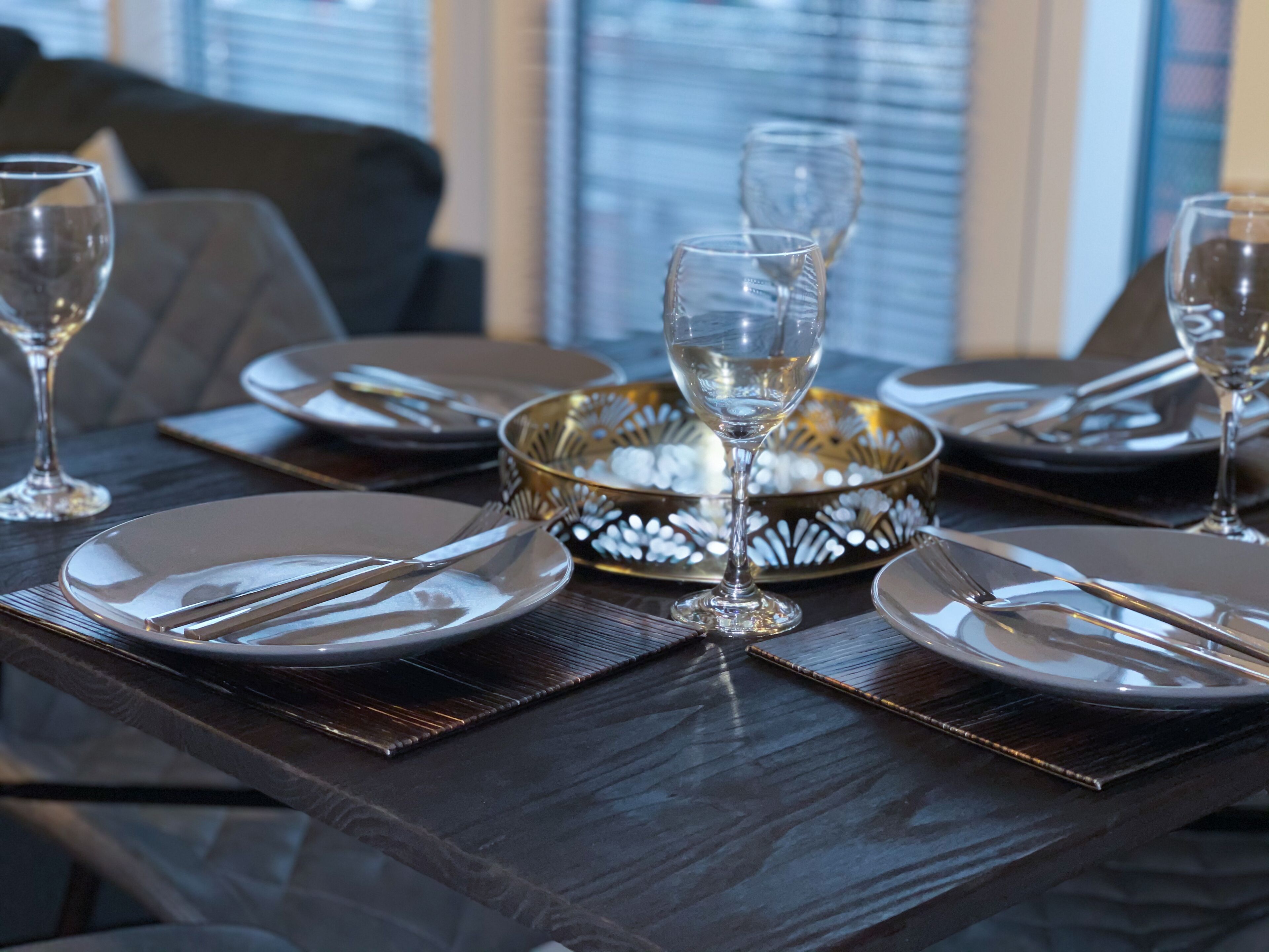 Una mesa de comedor dispuesta con platos, cubiertos y un cuenco decorativo.