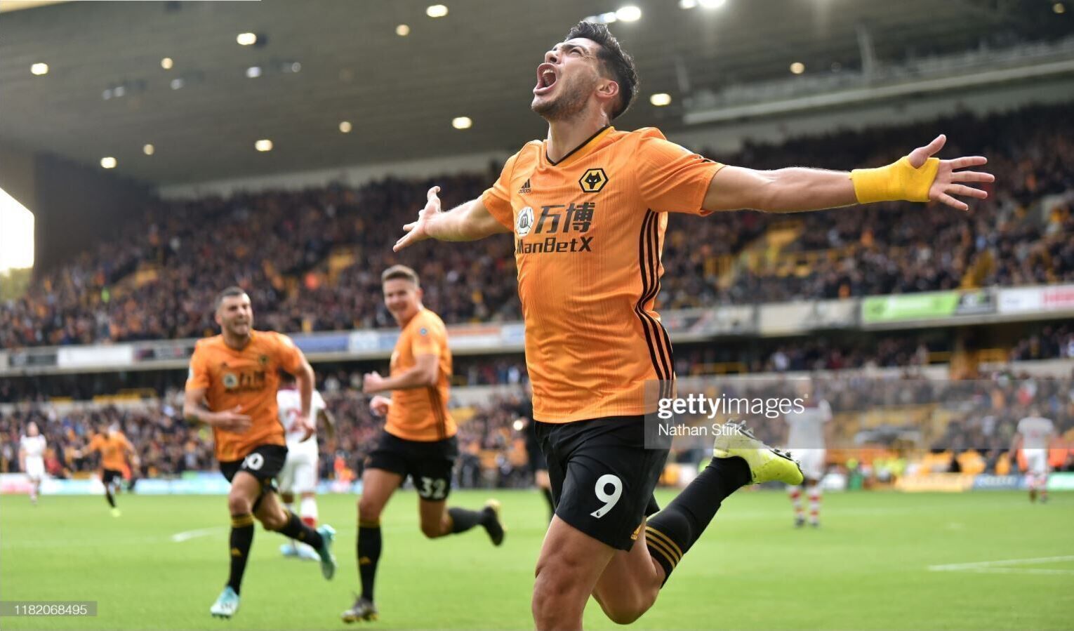 A soccer player in an orange jersey with the number 9, celebrating on the field.