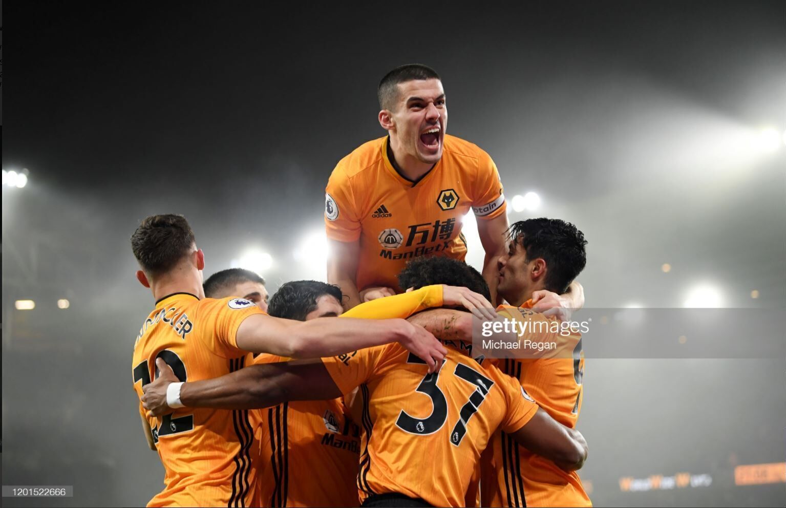 A group of soccer players in orange jerseys celebrating on a field.