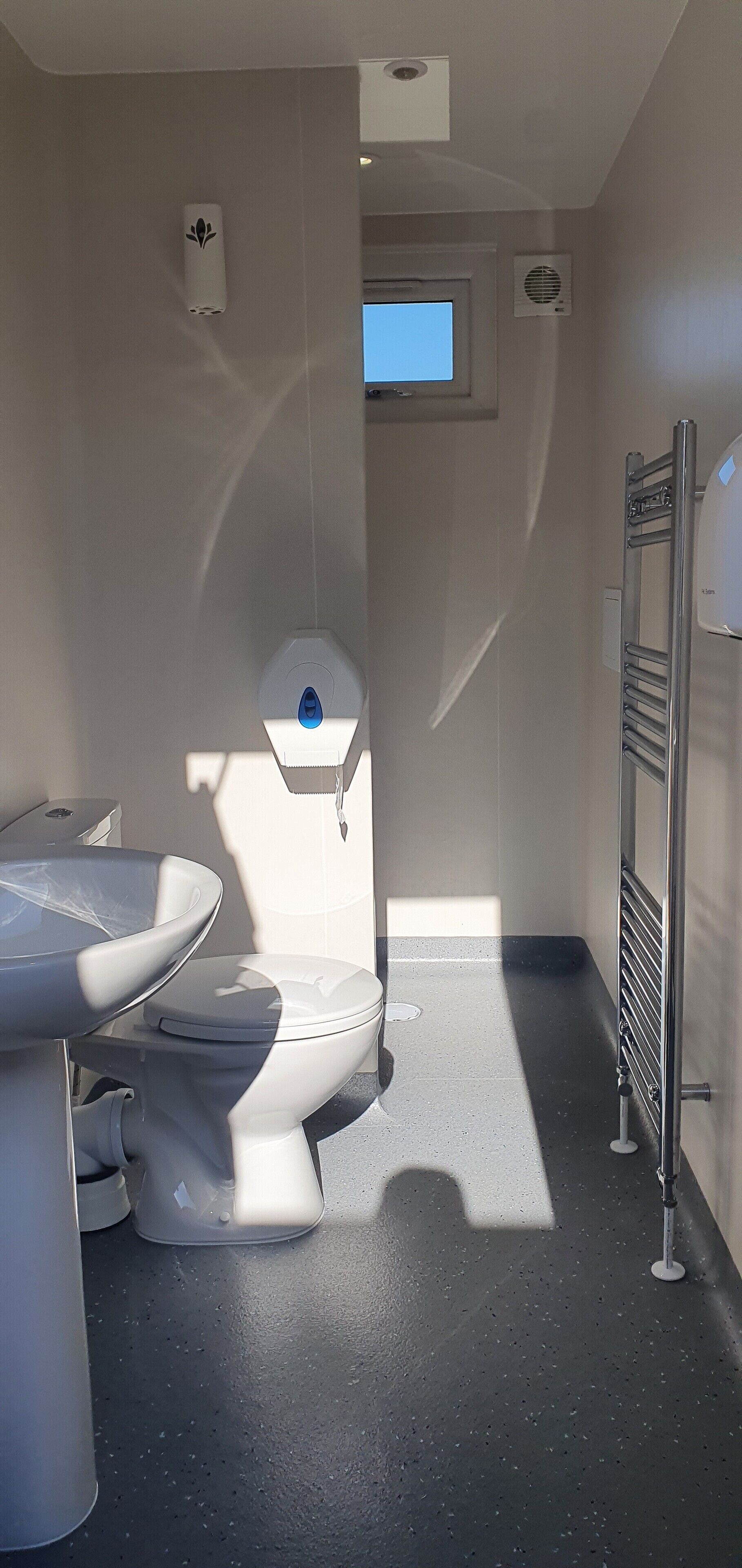Une petite salle de bain comprenant des toilettes, un lavabo et un porte-serviettes.