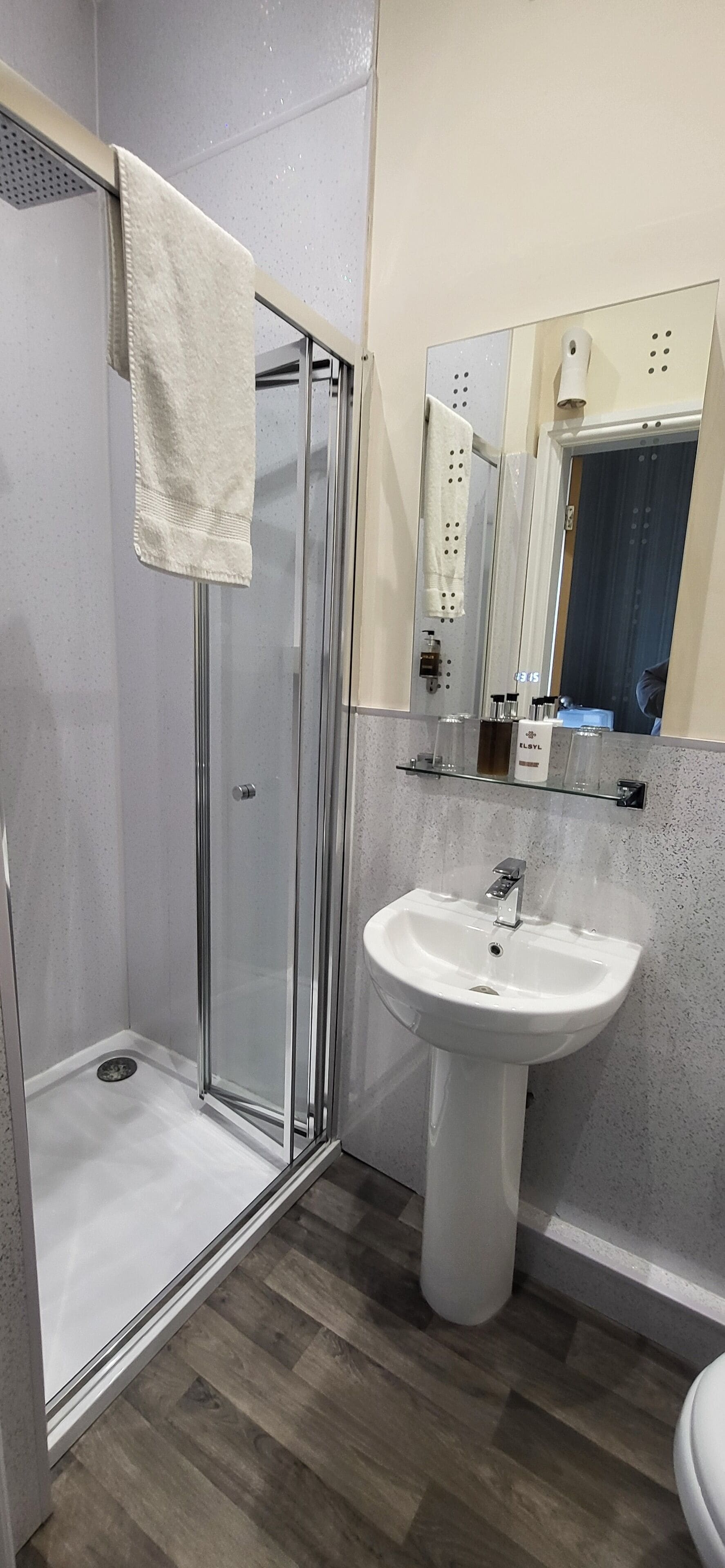 Une salle de bain avec une douche à parois de verre, un lavabo blanc et un miroir au-dessus du lavabo.