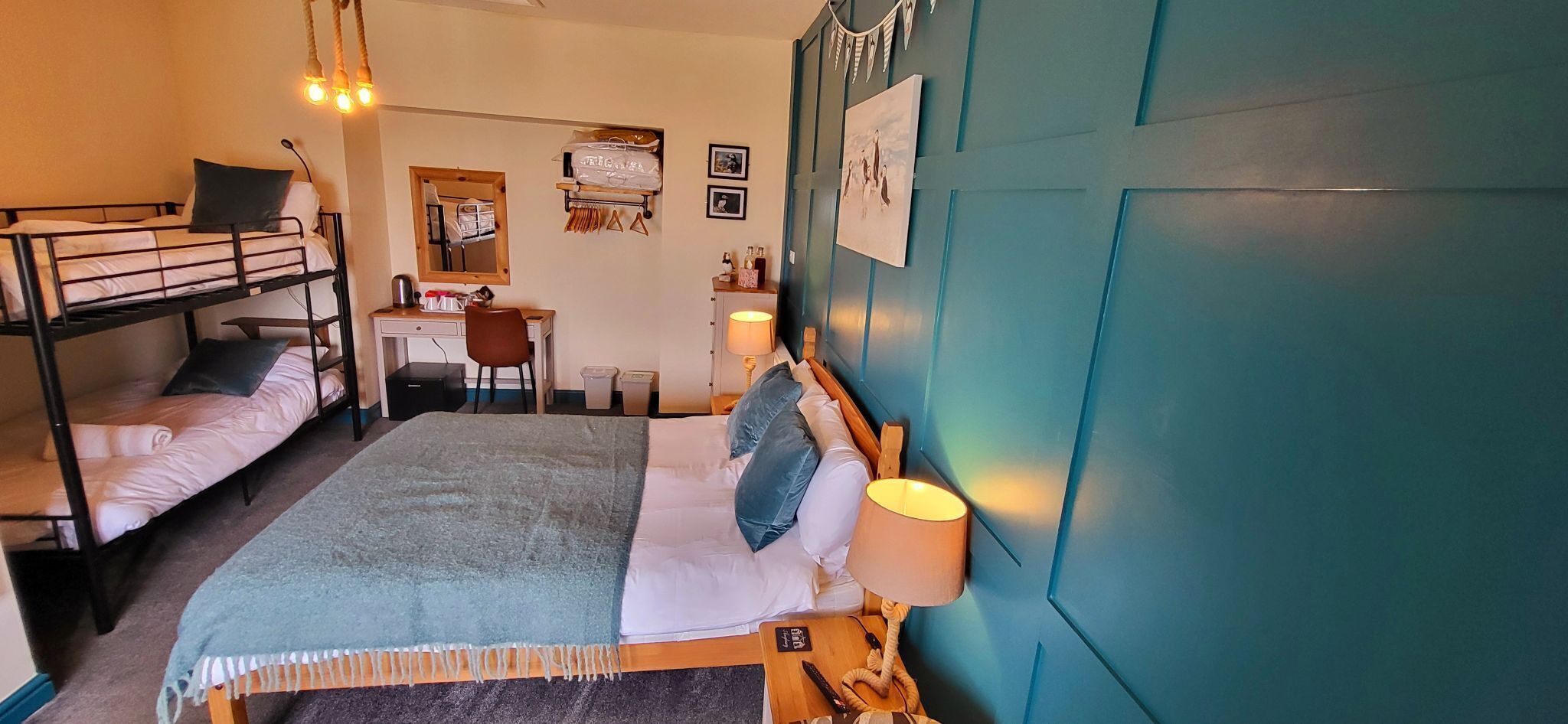 A dorm-style room with bunk beds, a desk, and a chair.