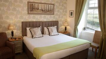 A neatly arranged bedroom with a large bed, two bedside tables, a chair, and a window with curtains.