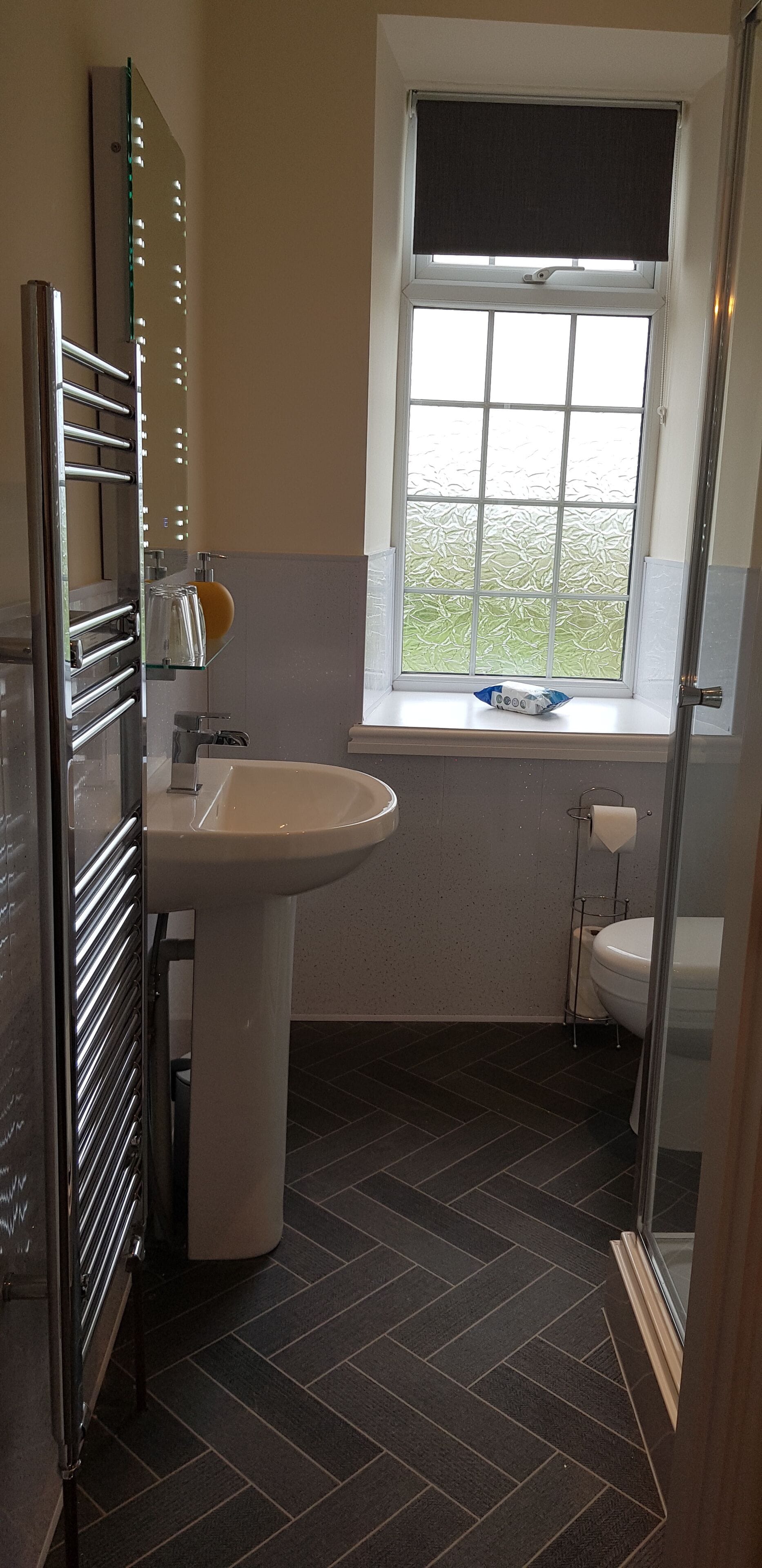 A bathroom with a sink, toilet, and window with blinds.