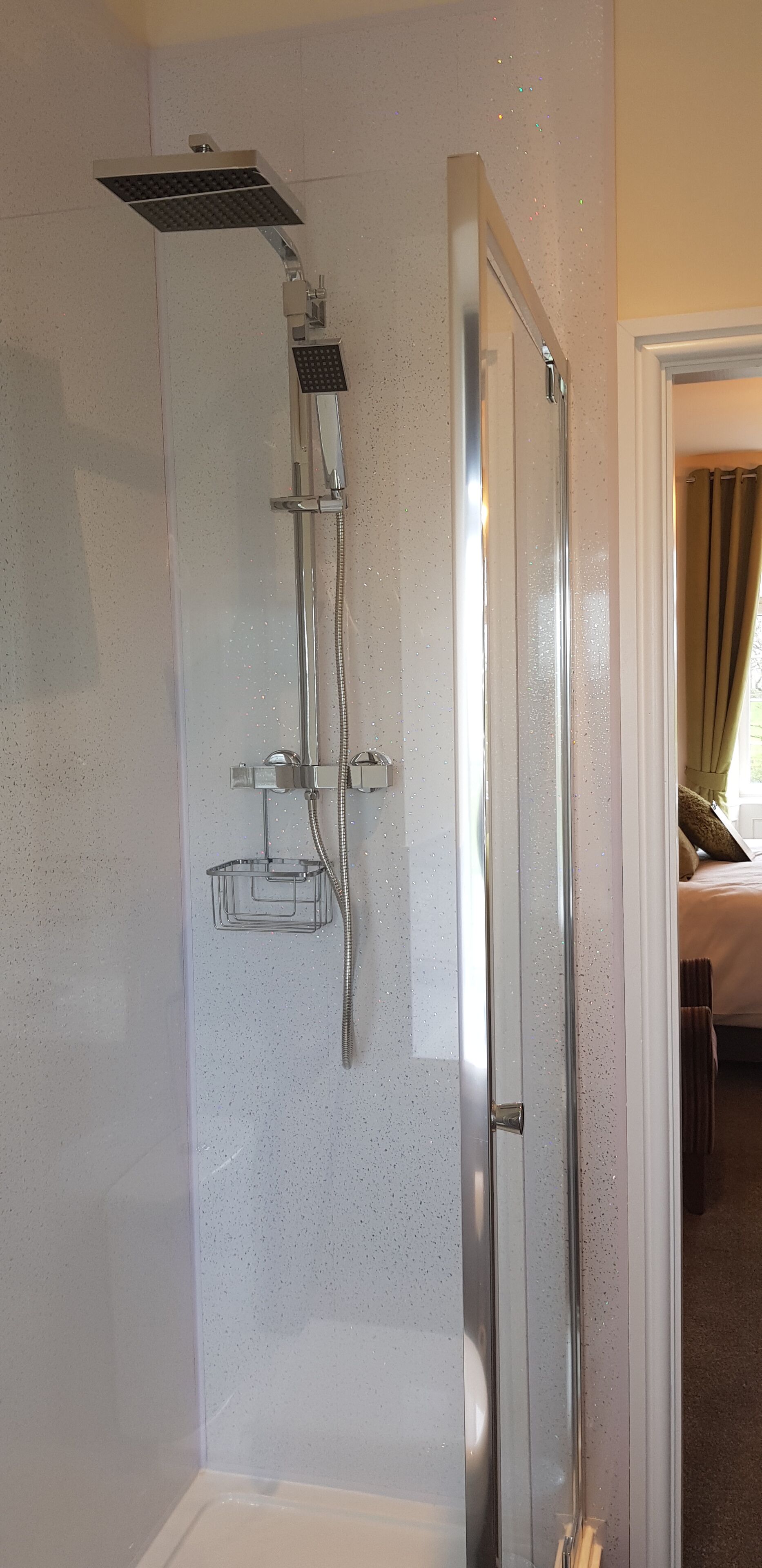 A shower with a handheld showerhead, a rain showerhead, and a handheld showerhead with a soap holder.