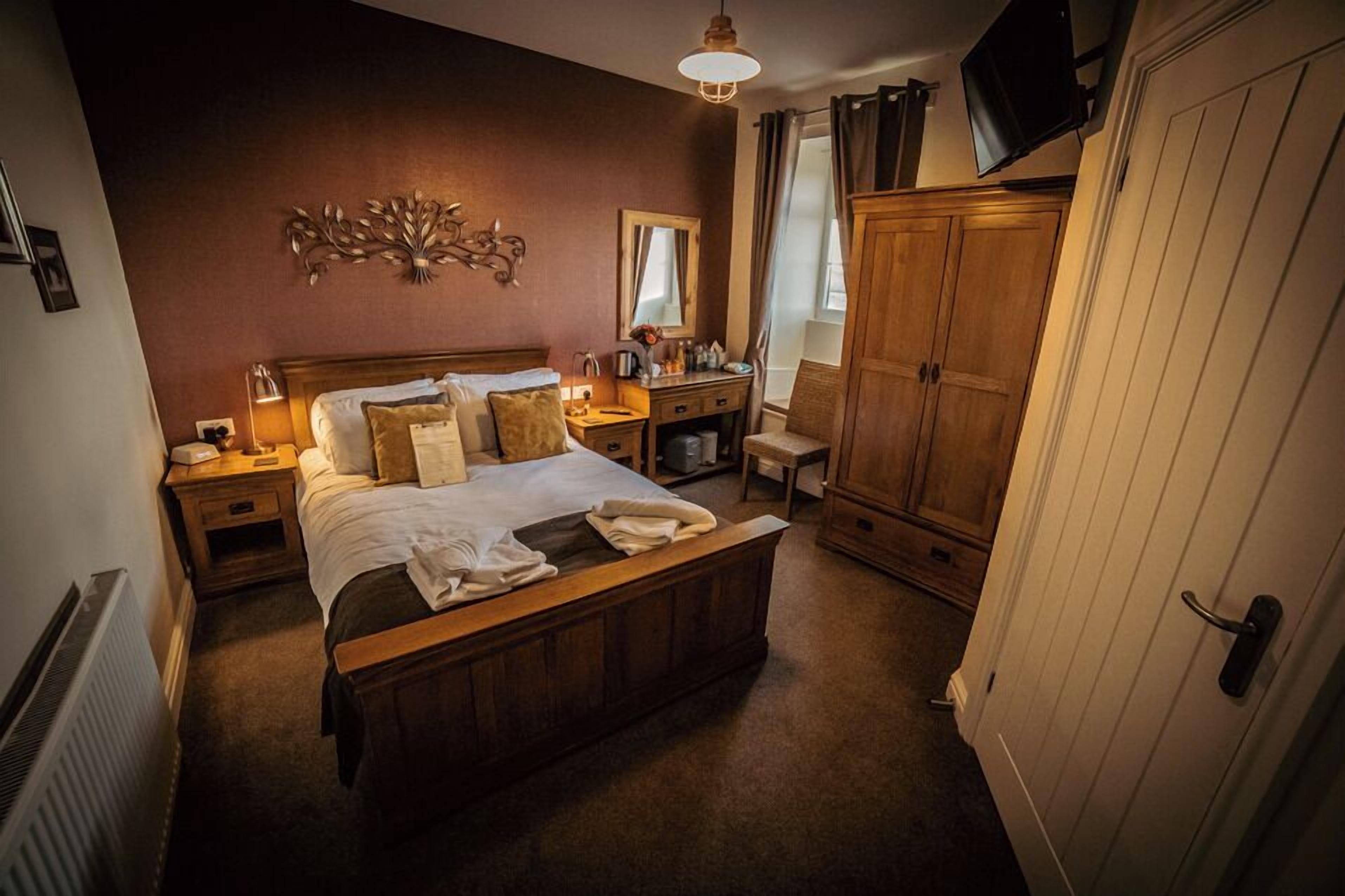 A bedroom with a wooden bed, nightstands, a dresser, a mirror, and a wardrobe.