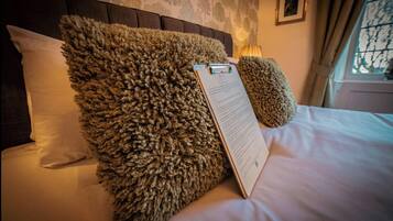 A neatly made bed with fluffy pillows and a clipboard on the bed.
