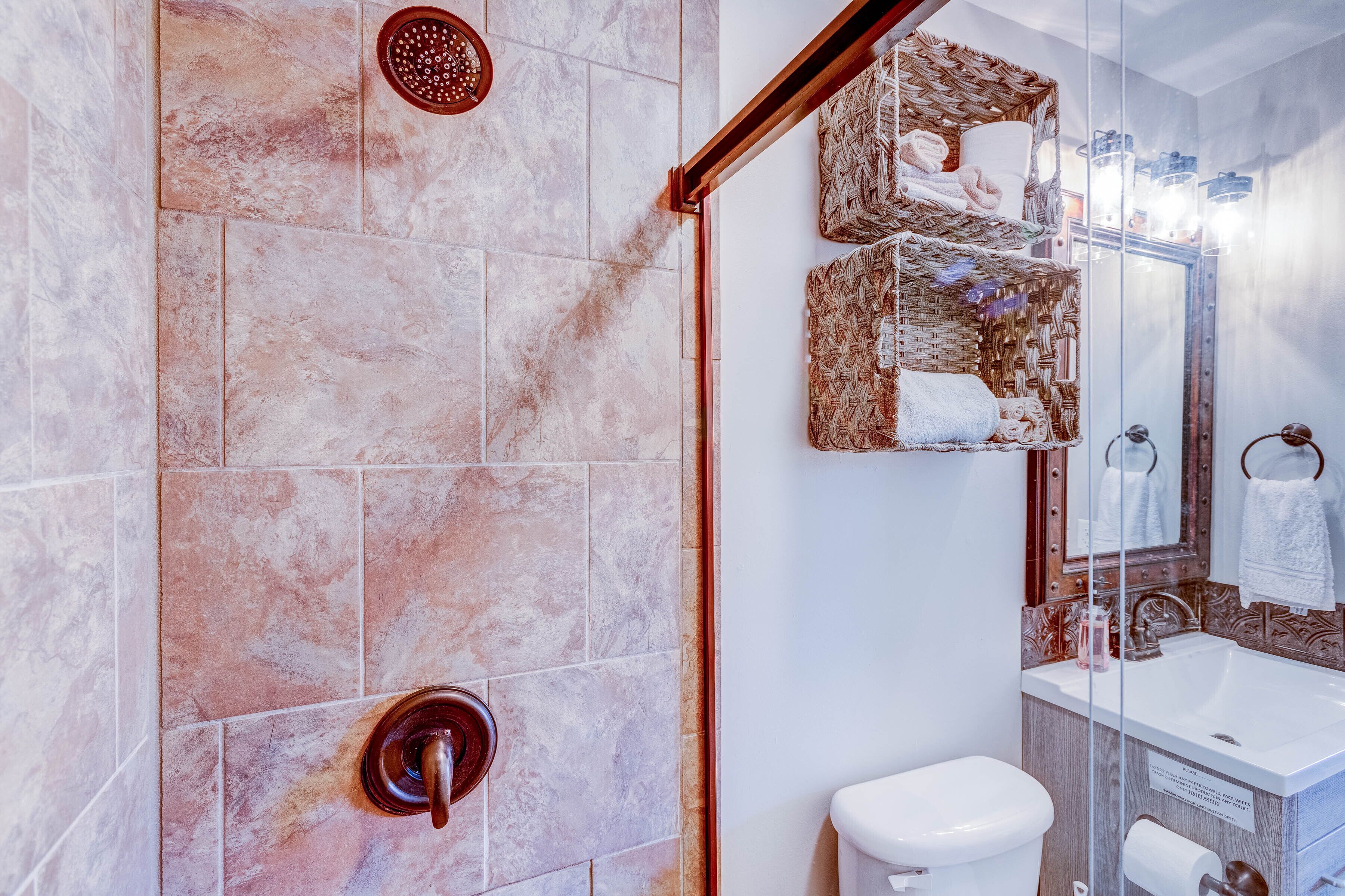 A modern bathroom with a shower, toilet, and sink.