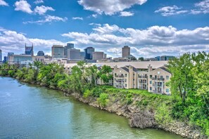 A riverside view of a city with modern buildings and a residential area with multi-story apartment buildings. - Downtown Riverfront condo ,walk to Honky Tonks (Nashville)