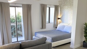 Una camera d'albergo moderna con divano, letto, tavolo da pranzo e un'ampia finestra.