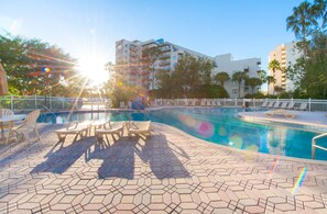 A swimming pool with lounge chairs and a tiled deck. - Modern Studio on I-Drive - pool + parking included (Orlando)