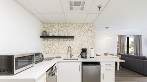 Una cucina moderna con mobili bianchi, forno a microonde integrato e lavastoviglie.
