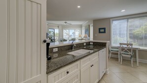 A modern kitchen with a double sink, granite countertop, and white cabinetry. - Fabulous ocean view from every room in this top floor villa in Palmetto Dunes (Hilton Head Island)