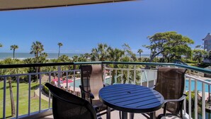 A balcony with a view of the ocean, a pool, and palm trees. - Fabulous ocean view from every room in this top floor villa in Palmetto Dunes (Hilton Head Island)