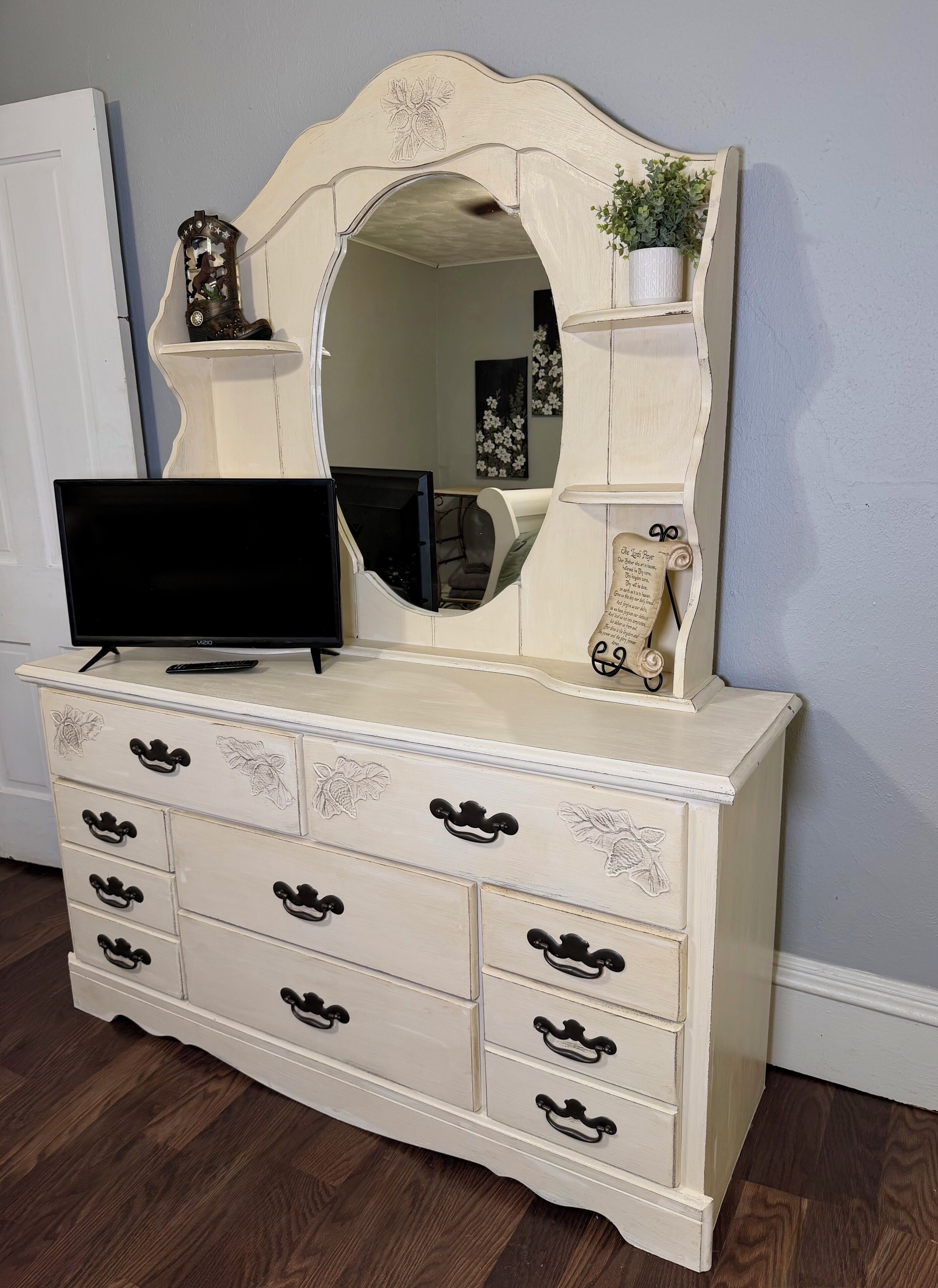 Een witte dressoir met spiegel, lades en een televisie erboven.