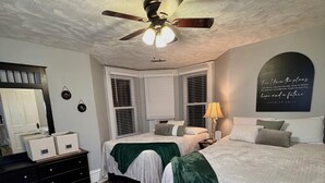 A bedroom with two beds, a ceiling fan, a large mirror, and a motivational quote on the wall. - Dexter Victorian Homestead- Brand NEW Remodel April 2026. VERY Clean & Cozy (Dexter)