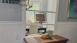 A kitchen area with a wooden countertop, a dark cabinet, a decorative plant, and a welcome sign. - Dexter Victorian Homestead- Brand NEW Remodel April 2026. VERY Clean & Cozy (Dexter)