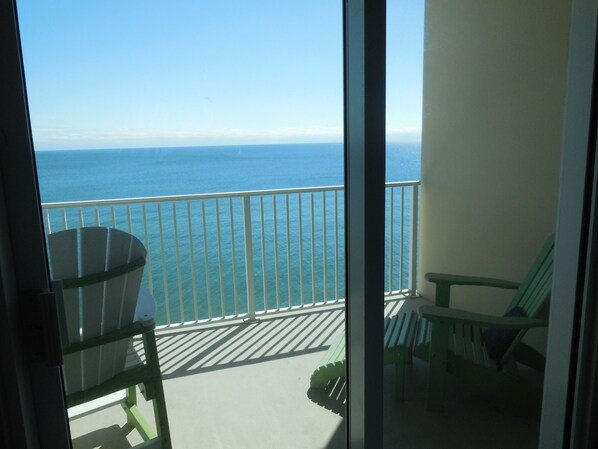 A balcony with a view of the sea, a chair, and a table.