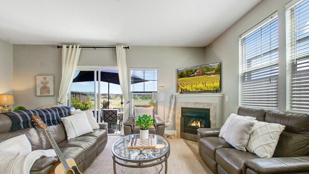 A living room with a fireplace, leather sofas, a glass coffee table, and a guitar.