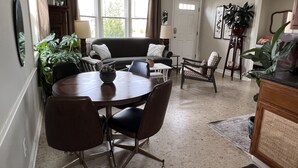 A dining area with a round table, chairs, a sofa, and a potted plant. - Comfy, Remodeled Beach House with Vintage Jersey Shore Charm (Lavallette)