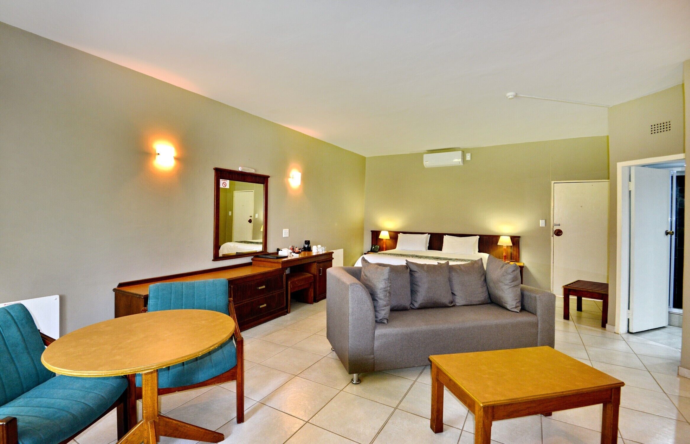 Een hotelkamer met een bed, een slaapbank, een eettafel, een bureau en een stoel.