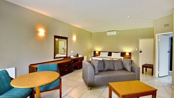 Een hotelkamer met een bed, een slaapbank, een eettafel, een bureau en een stoel.