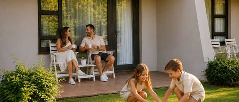 Una familia de cuatro personas en un patio con césped, una mesa de comedor y sillas.