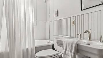 Un baño con inodoro, lavamanos y cortina de ducha.