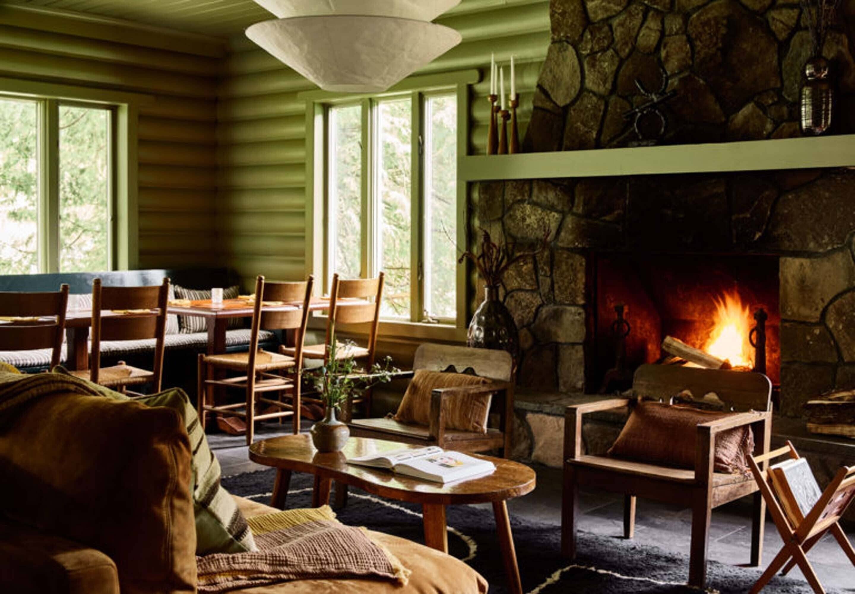 Un salon chaleureux avec une cheminée en pierre, des meubles en bois et de grandes fenêtres.
