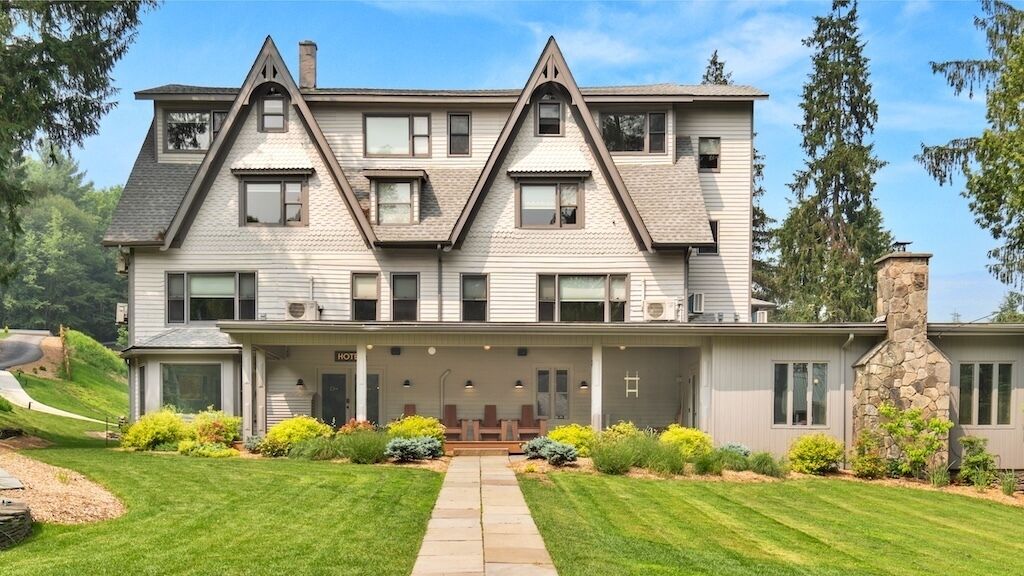 A two-story house with a symmetrical facade, a central entrance, and a stone chimney.