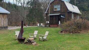Una casa de madera rústica con chimenea, un hoyo de fuego y asientos al aire libre.