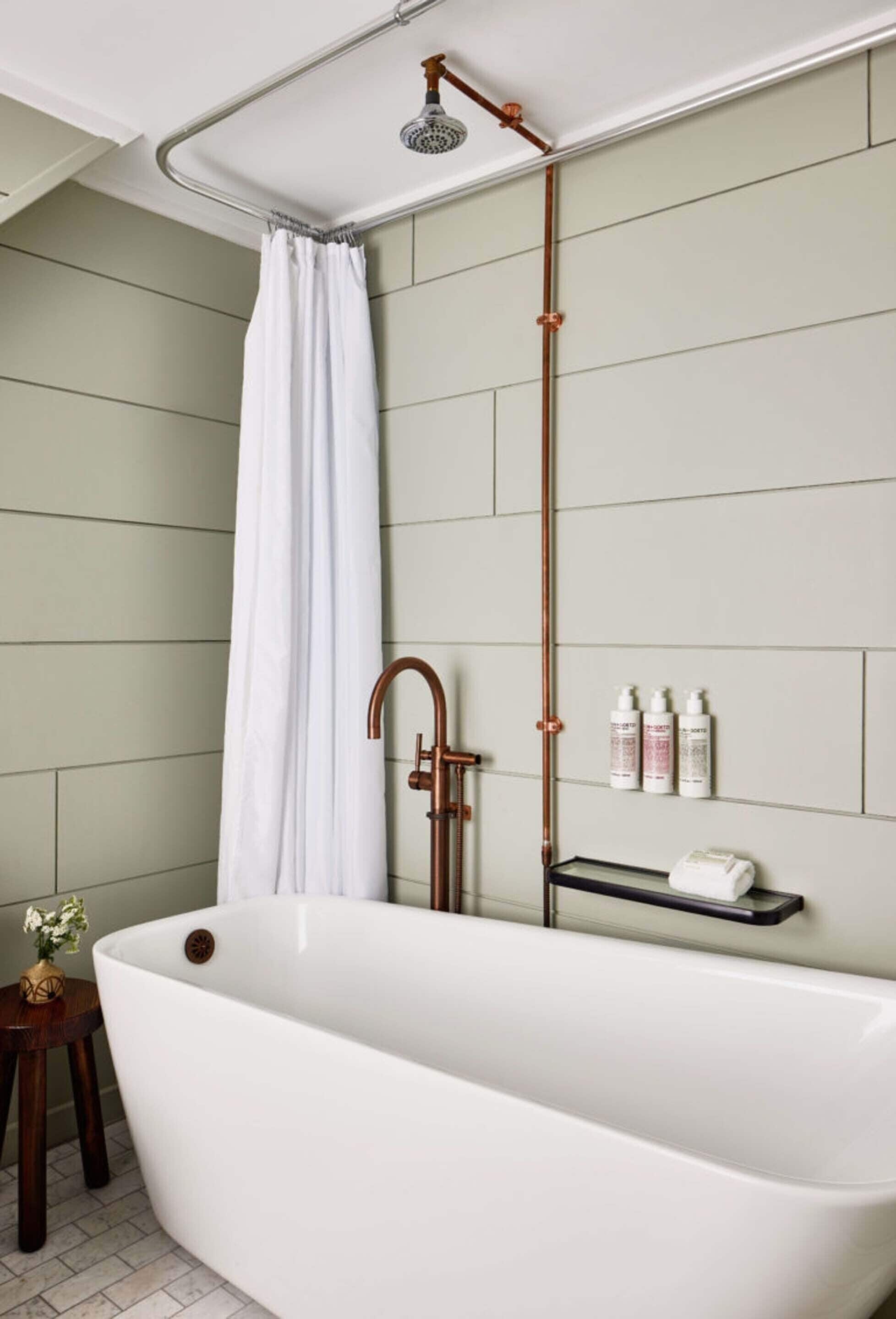 A modern bathroom with a freestanding bathtub, a showerhead, and a towel rack.
